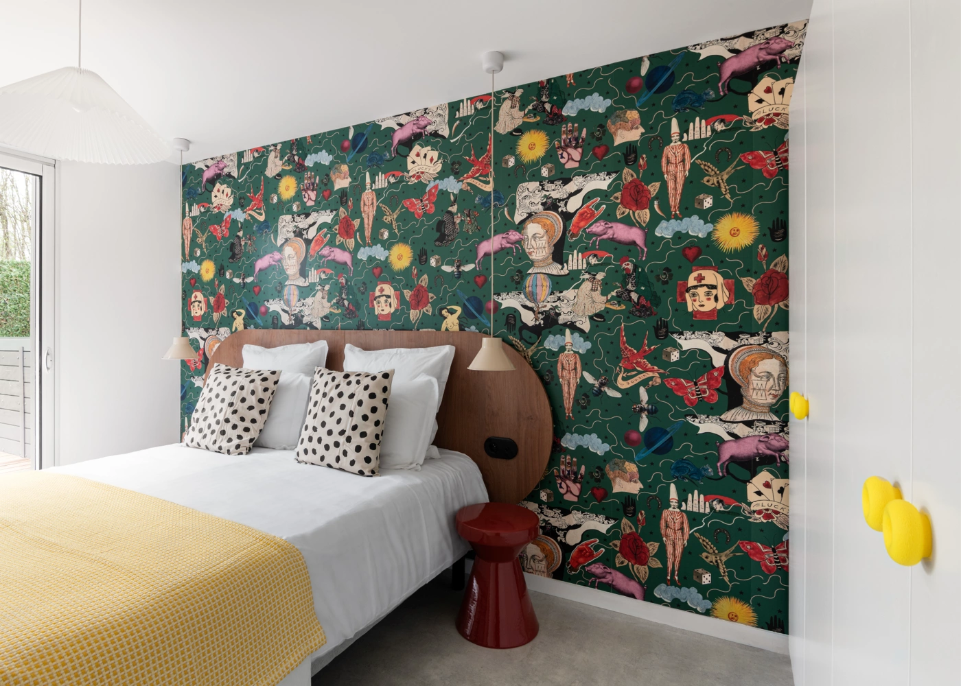 Airbnb déco chambre papier peint tattoo vert forêt : lit double avec jeté jaune, chevet rouge vintage et crochet jaune mural, gîte premium Côte d'Émeraude