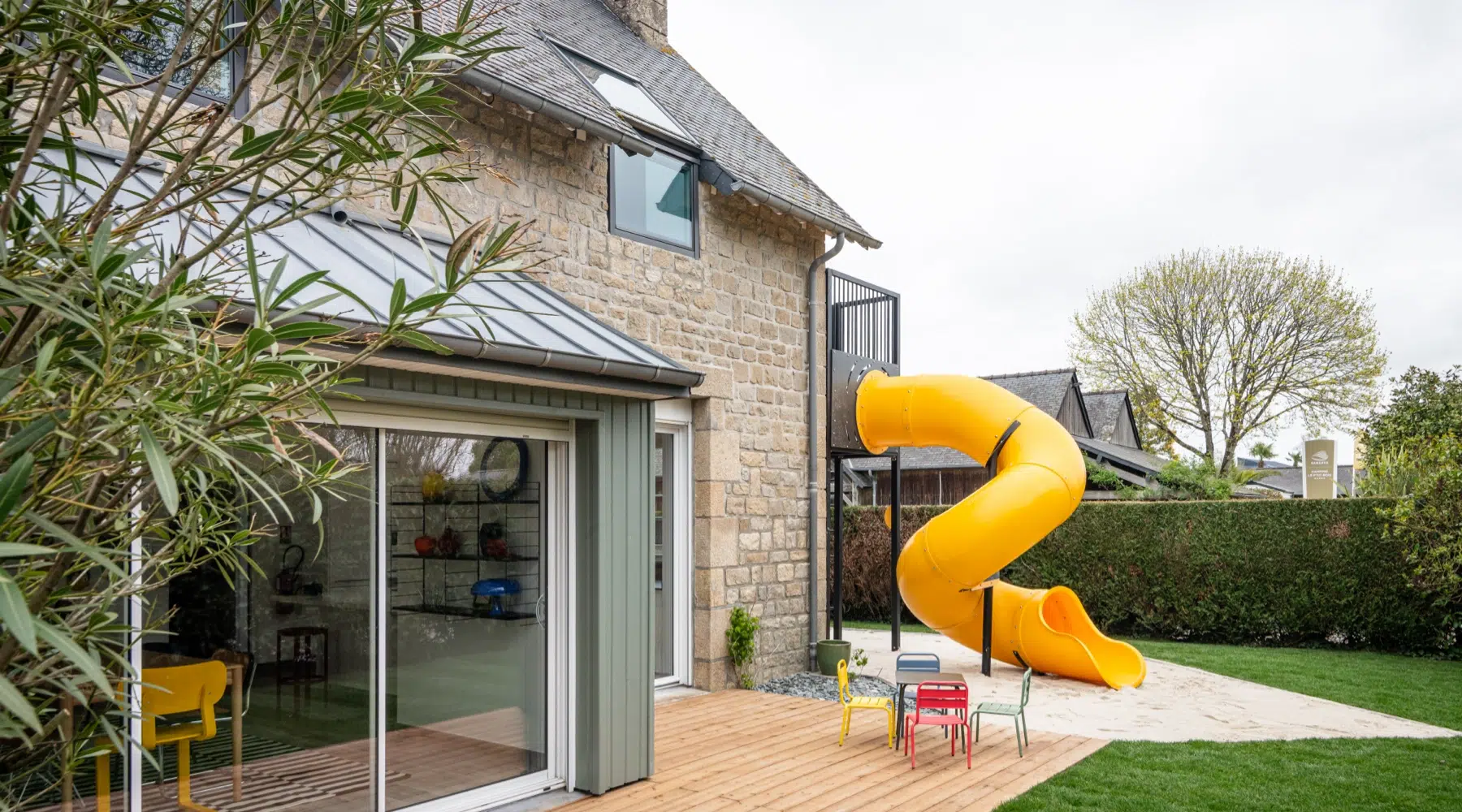 Airbnb déco extérieur kids friendly : toboggan jaune géant, terrasse bois et jardin aménagé, gîte premium Côte d'Émeraude