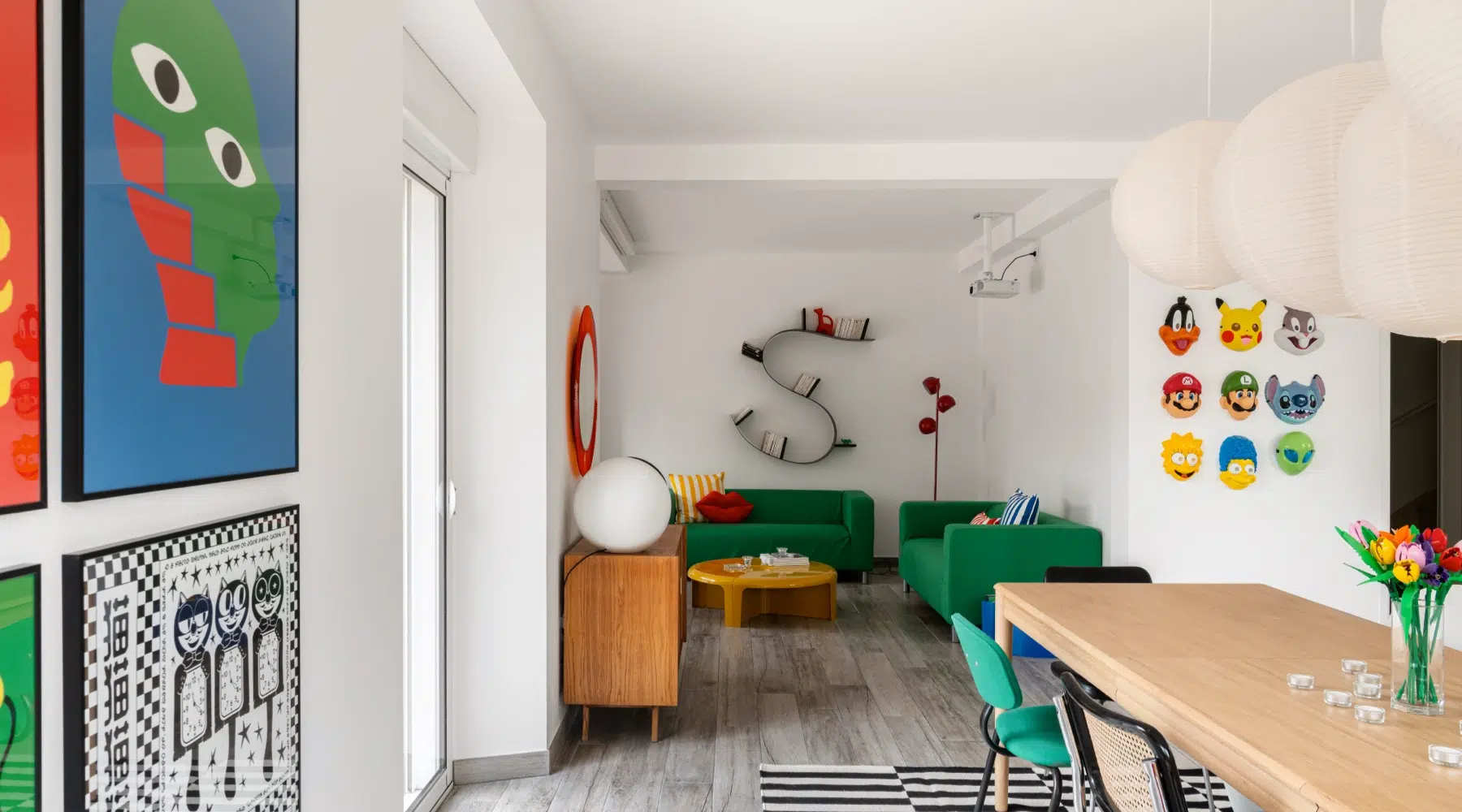 Airbnb déco graphique : espace de vie ouvert avec canapé vert, étagère vintage et décoration pop culture, gîte premium Côte d'Émeraude