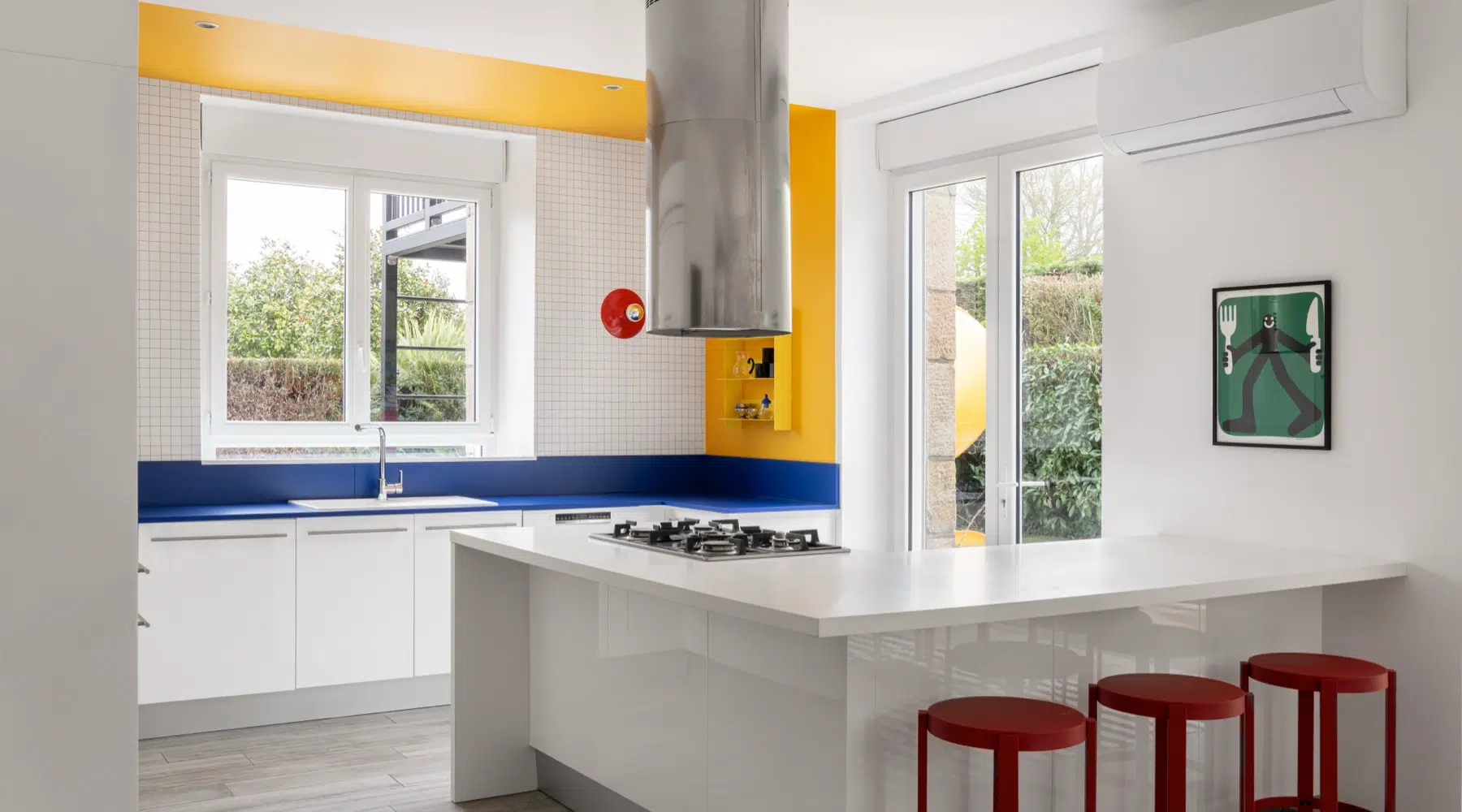 Airbnb déco cuisine jaune et bleue : plan de travail bleu Klein, tabourets rouges et carrelage blanc, gîte kids friendly Bretagne