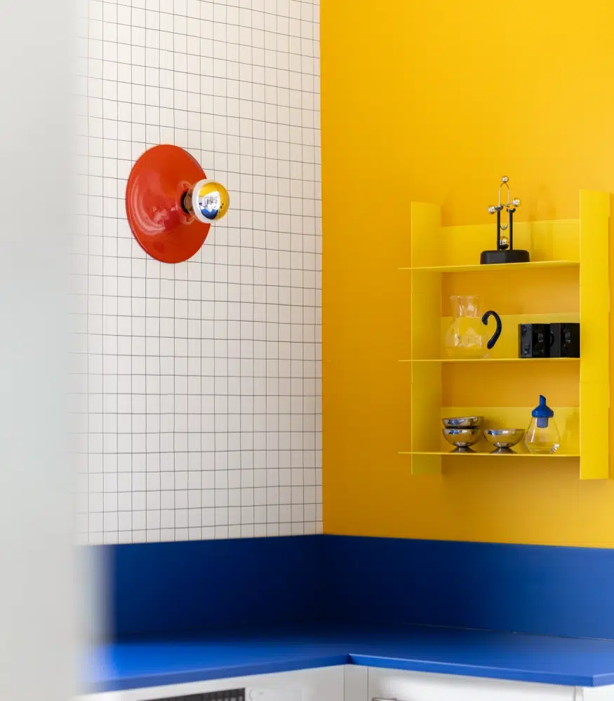 Airbnb déco cuisine colorée : îlot central blanc, mur jaune solaire et détails rouges, logement saisonnier design Saint-Jouan-des-Guérets