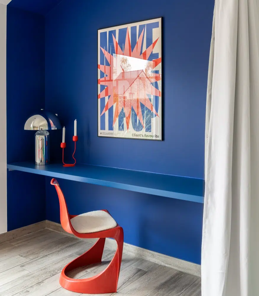 Airbnb déco chambre bleue cobalt : espace bureau avec chaise rouge design et étagère murale, gîte premium Côte d'Émeraude