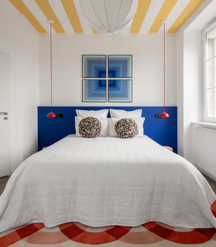 Airbnb déco chambre principale : tête de lit bleue cobalt et tableaux op art en quadriptyque, logement saisonnier design Bretagne